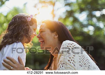 Stock Image - Enthusiastic mother and daughter smiling face to face. Fotosearch