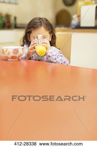 Girl drinking orange juice at breakfast table View Large Photo Image Stock Photo - Girl drinking orange juice at breakfast table. Fotosearch