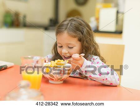 Girl eating cereal at breakfast table View Large Photo Image Stock Image - Girl eating cereal at breakfast table. Fotosearch