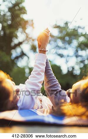 Stock Photograph - Girls laying holding hands in park. Fotosearch