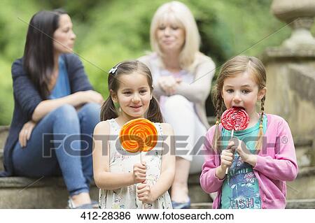 Girls with lollipops in park View Large Photo Image Stock Photograph - Girls with lollipops in park. Fotosearch
