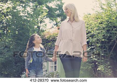 Grandmother and granddaughter holding hands and walking in garden View Large Photo Image Stock Image - Grandmother and granddaughter holding hands and walking in garden. Fotosearch