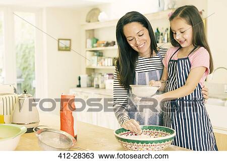 Mother and daughter baking sifting flour in kitchen View Large Photo Image Stock Image - Mother and daughter baking sifting flour in kitchen. Fotosearch