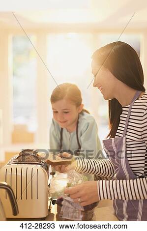 Mother and daughter toasting bread in kitchen View Large Photo Image Stock Image - Mother and daughter toasting bread in kitchen. Fotosearch