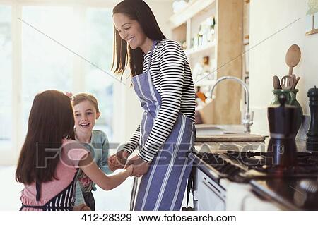 Mother and daughters holding hands in kitchen View Large Photo Image Stock Photo - Mother and daughters holding hands in kitchen. Fotosearch