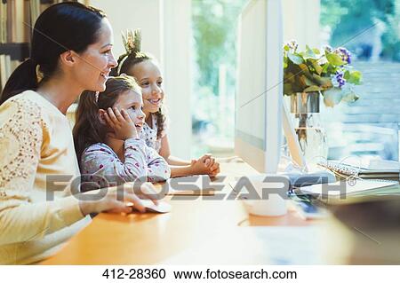 Stock Image - Mother and daughters using computer. Fotosearch