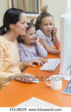 Stock Photo - Mother and daughters using computer. Fotosearch