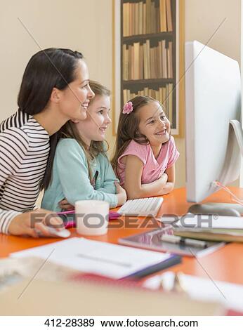 Stock Photo - Mother and daughters using computer. Fotosearch
