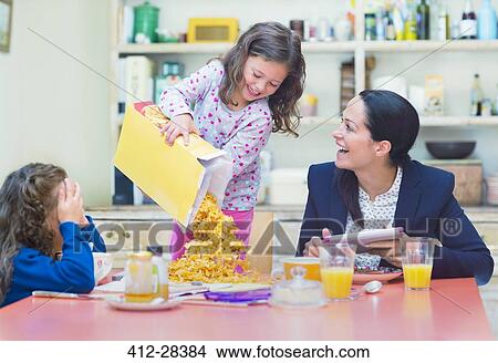 Playful girl pouring abundance of cereal onto breakfast table View Large Photo Image Picture - Playful girl pouring abundance of cereal onto breakfast table. Fotosearch