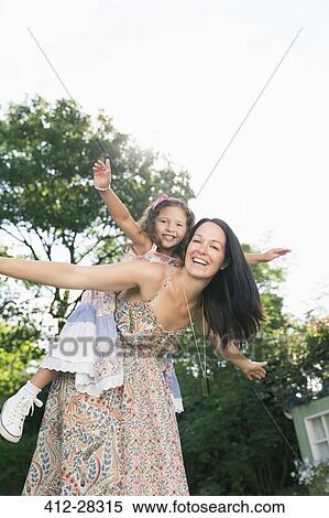 Portrait carefree mother piggybacking daughter with arms outstretched View Large Photo Image Stock Photography - Portrait carefree mother piggybacking daughter with arms outstretched. Fotosearch