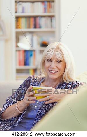 Portrait smiling senior woman drinking coffee on sofa View Large Photo Image Stock Image - Portrait smiling senior woman drinking coffee on sofa. Fotosearch