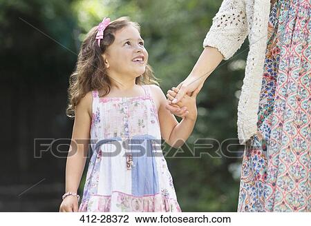 Stock Image - Smiling girl in dress holding mother's hand. Fotosearch