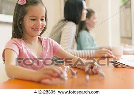 Stock Photography - Smiling girl playing with miniature toy animals. Fotosearch