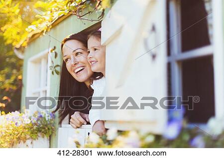 Stock Image - Smiling mother and daughter in playhouse window. Fotosearch