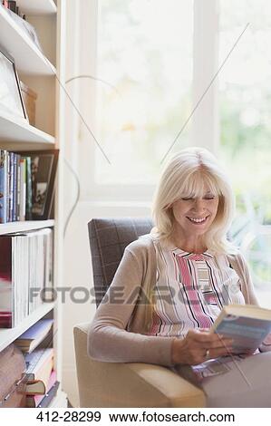 Smiling senior woman reading book in den View Large Photo Image Stock Photo - Smiling senior woman reading book in den. Fotosearch