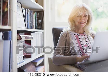 Smiling senior woman using laptop in den View Large Photo Image Stock Image - Smiling senior woman using laptop in den. Fotosearch
