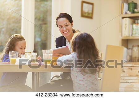 Working mother and daughters at breakfast table View Large Photo Image Picture - Working mother and daughters at breakfast table. Fotosearch