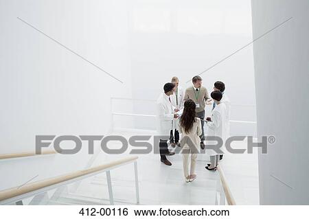 Stock Photograph - Business people and doctors on landing of stairs. Fotosearch