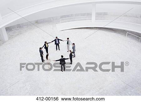Business people holding hands in circle in courtyard View Large Photo Image Stock Photograph - Business people holding hands in circle in courtyard. Fotosearch