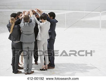 Business people standing in huddle with arms raised View Large Photo Image Stock Image - Business people standing in huddle with arms raised. Fotosearch