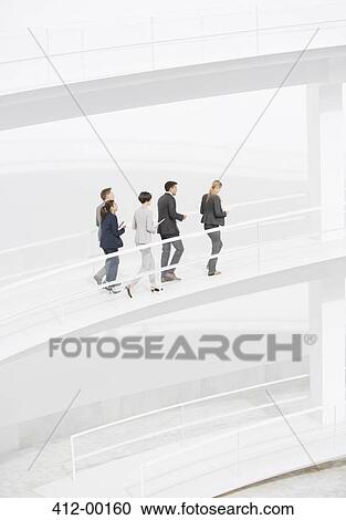 Business people walking along elevated walkway View Large Photo Image Stock Image - Business people walking along elevated walkway. Fotosearch