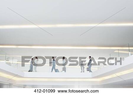 Stock Photo - Business people walking along elevated walkway in airport. Fotosearch