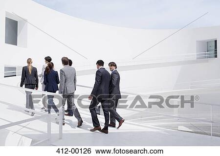 Stock Photograph - Business people walking up elevated walkway. Fotosearch