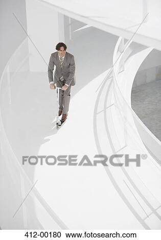 Businessman riding scooter down elevated walkway View Large Photo Image Stock Image - Businessman riding scooter down elevated walkway. Fotosearch