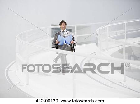 Businessman sitting in chair with folder on elevated walkway View Large Photo Image Stock Image - Businessman sitting in chair with folder on elevated walkway. Fotosearch