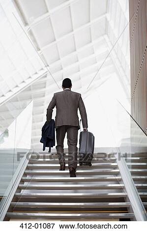 Stock Photo - Businessman with suitcase ascending stairs. Fotosearch
