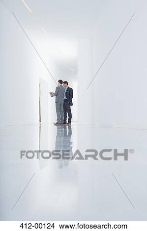 Businessmen with digital tablet in corridor View Large Photo Image Picture - Businessmen with digital tablet in corridor. Fotosearch