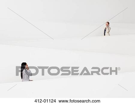 Businesswomen talking on cell phones on modern staircase View Large Photo Image Picture - Businesswomen talking on cell phones on modern staircase. Fotosearch