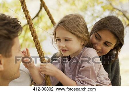 Stock Image - Close up of family on swing. Fotosearch