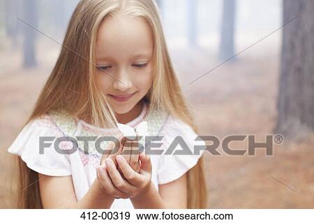 Stock Photo - Close up of girl holding butterfly in woods. Fotosearch