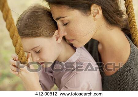 Stock Image - Close up of serene mother and daughter on swing. Fotosearch