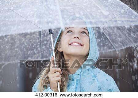 Stock Photograph - Close up of smiling girl under umbrella in downpour. Fotosearch