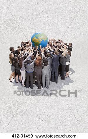 Crowd of business people in huddle lifting globe overhead View Large Photo Image Stock Photo - Crowd of business people in huddle lifting globe overhead. Fotosearch