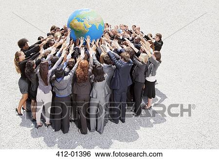Stock Photograph - Crowd of business people in huddle reaching for globe. Fotosearch