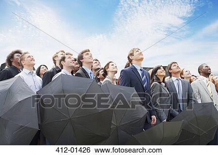Crowd of business people with umbrellas looking up at sky View Large Photo Image Stock Photograph - Crowd of business people with umbrellas looking up at sky. Fotosearch