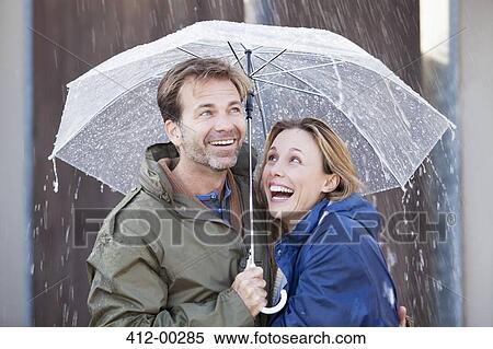 Stock Photography - Happy couple under umbrella in downpour. Fotosearch