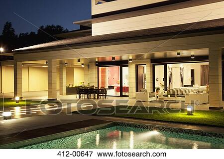 Stock Photo - Luxury house and swimming pool illuminated at night. Fotosearch