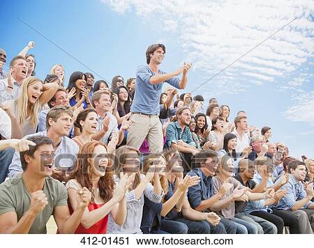 Man standing and clapping among cheering crowd View Large Photo Image Stock Image - Man standing and clapping among cheering crowd. Fotosearch