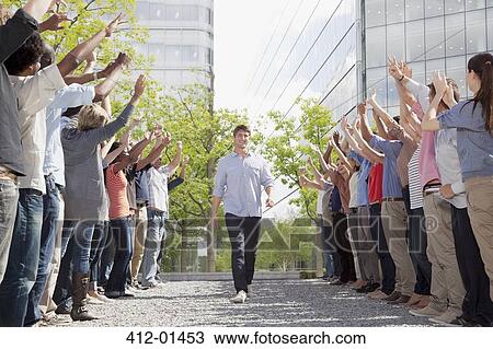 Stock Image - Man walking between cheering crowd. Fotosearch