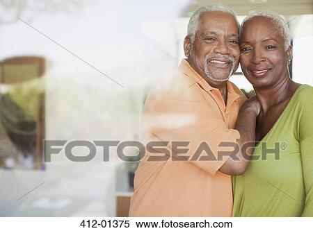 Stock Photography - Older couple smiling by window. Fotosearch