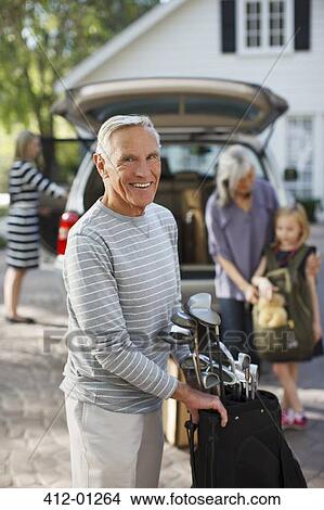 Picture - Older man carrying golf clubs in bag. Fotosearch