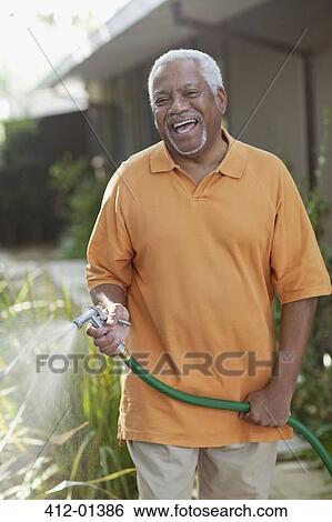 Older men watering plants in backyard View Large Photo Image Stock Photograph - Older men watering plants in backyard. Fotosearch