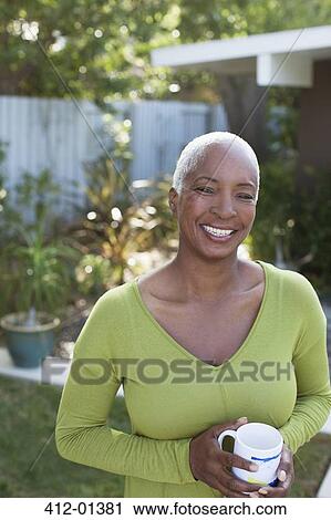 Older woman having cup of coffee in backyard View Large Photo Image Stock Image - Older woman having cup of coffee in backyard. Fotosearch