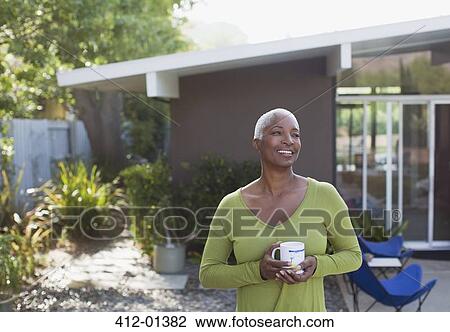 Older woman having cup of coffee in backyard View Large Photo Image Stock Image - Older woman having cup of coffee in backyard. Fotosearch