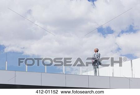 Pensive businessman looking up at sky on rooftop balcony View Large Photo Image Stock Image - Pensive businessman looking up at sky on rooftop balcony. Fotosearch
