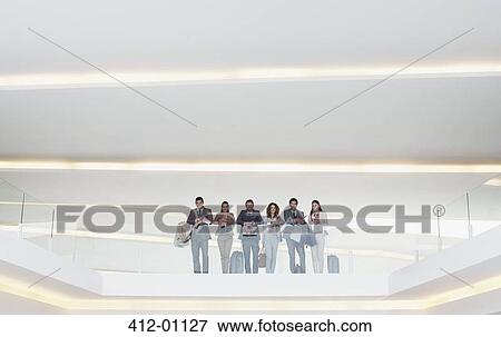 Portrait of business people standing at glass balcony railing in modern office View Large Photo Image Stock Photo - Portrait of business people standing at glass balcony railing in modern office. Fotosearch
